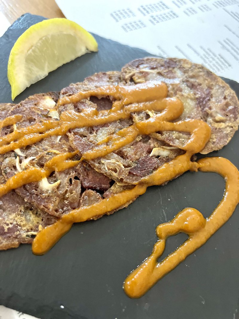 A serving of creisly ear pancakes with brava sauce.