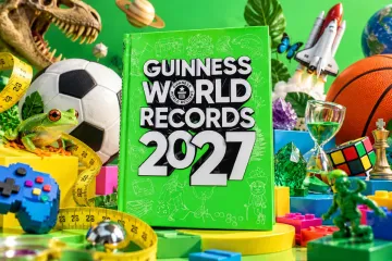 Green-covered Guinness World Records 2027 book surrounded by a football, a frog, a Rubik's cube, a rocket and other objects