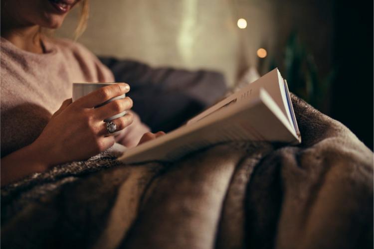 Mujer leyendo un libro en la cama.