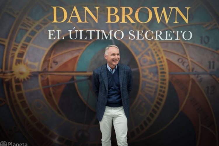 Retrato de Dan Brown, autor, enfrente de la portada de su libro titulado el último secreto - cortesía de Liven Photography.