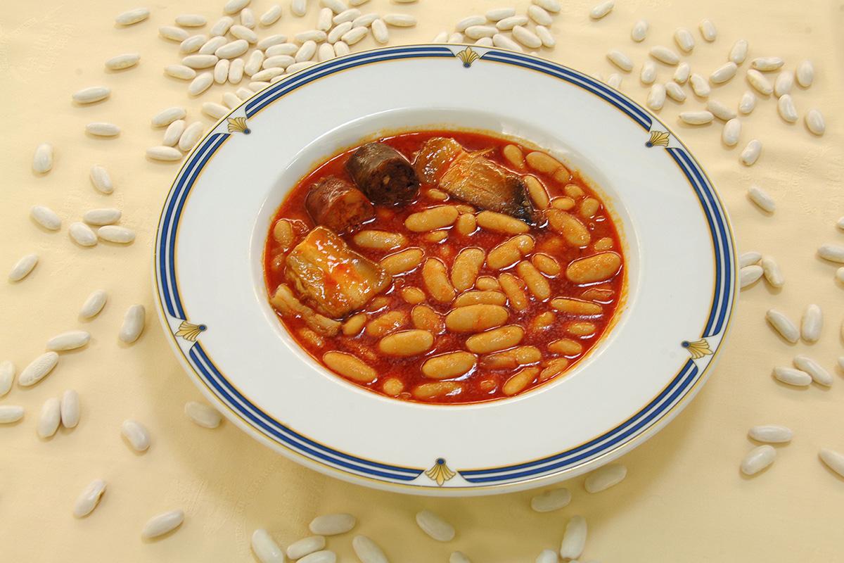 A plat of fabada surrounded with white beans.